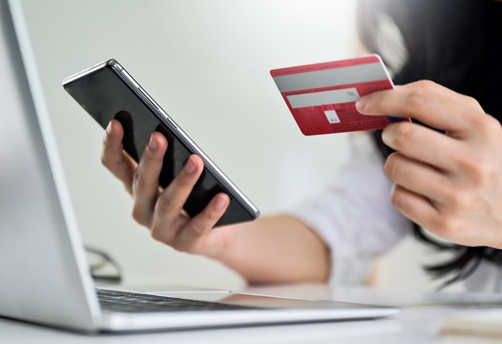 Una persona mira su móvil mientras sujeta una tarjeta de crédito
